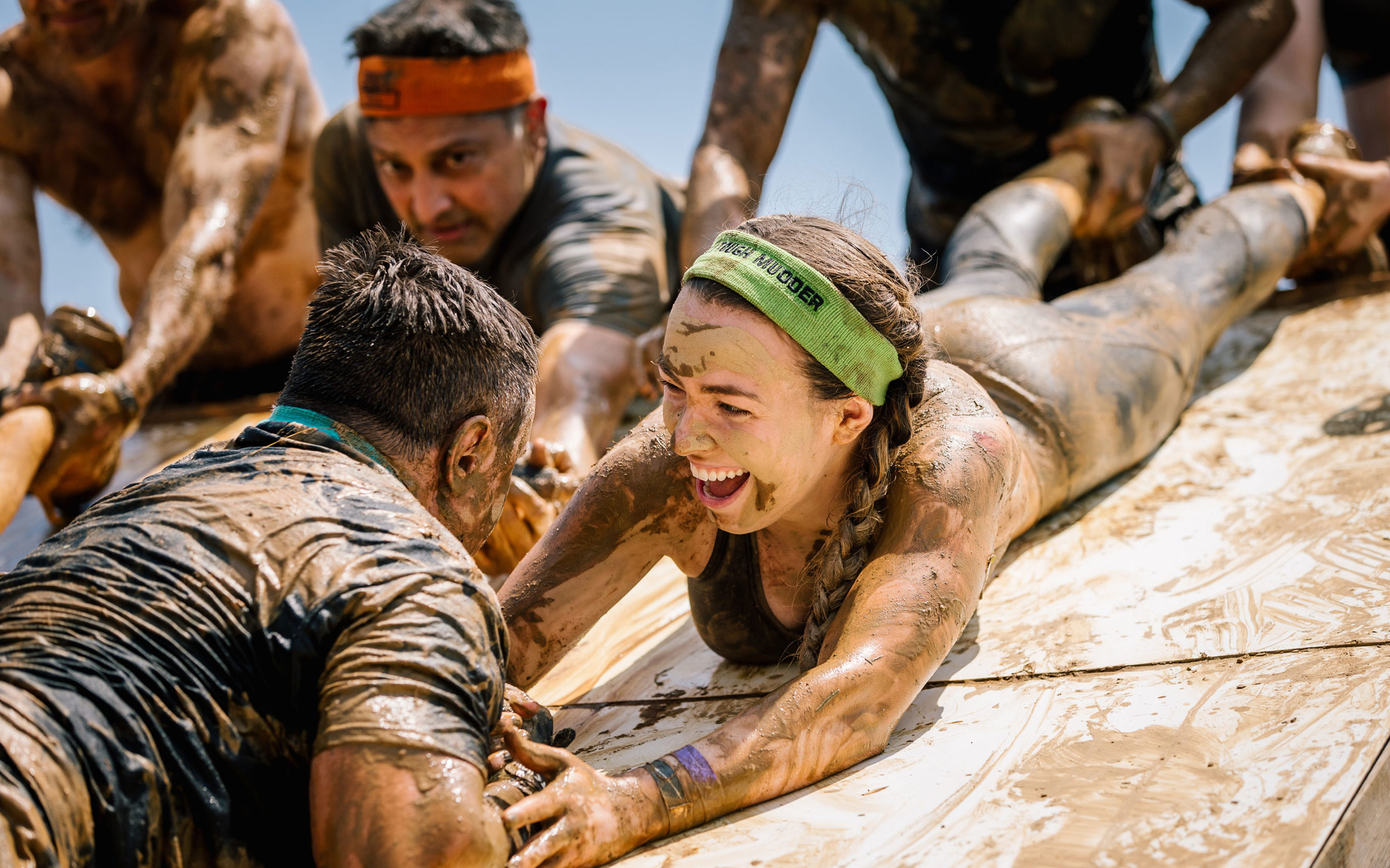 Participant smiling while holding the hand of her teammate to help him climb