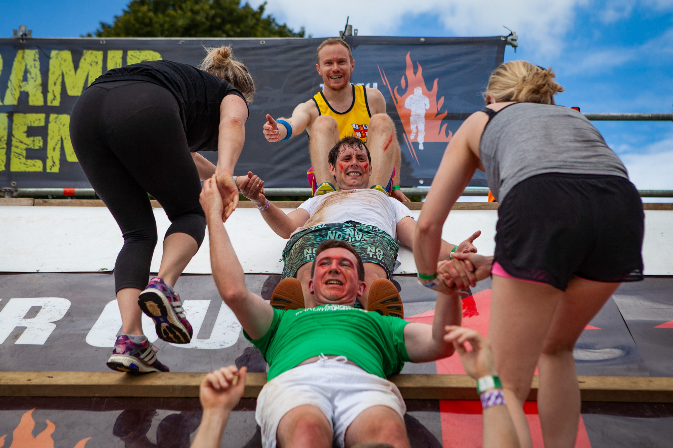 A team help each other up the obstacle