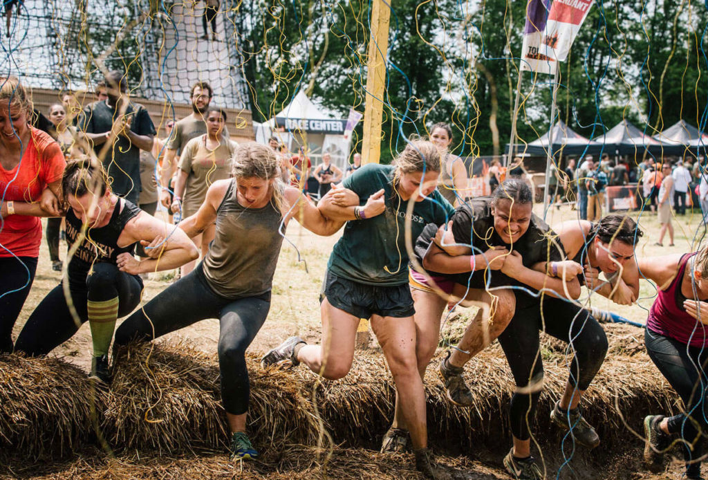 team linked arms mud obstacle