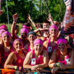 A group of participants with their pink finisher shirts and pink headbands smiling happily