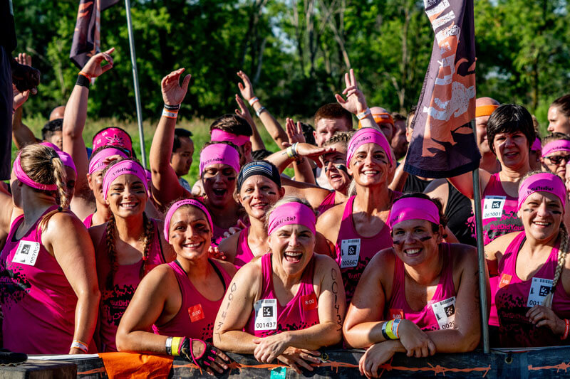 A group of participants with their pink finisher shirts and pink headbands smiling happily