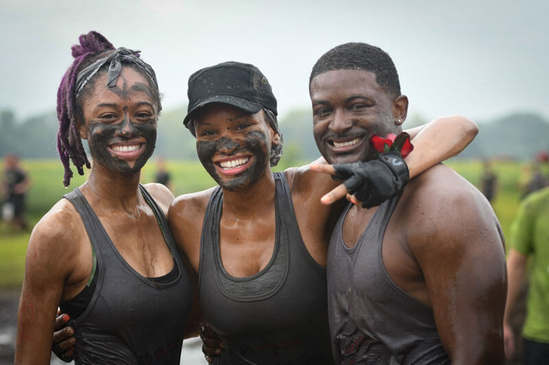 Three participants posing for a picture with mud in their faces