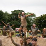 A group of participants covered in mud while cheering