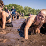 Participants smilling while crawling in the mud