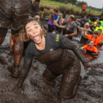 Participants smiling widely while in the mud