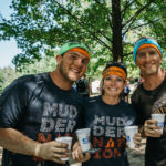Participants smiling for a picture with beers in their hands and wearing their exclusive headbands