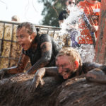 girls laughing in mud water obstacle