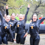 four girls water obstacle Tough Mudder outside in summer