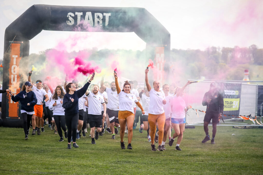 runners with flares through Tough Mudder start line