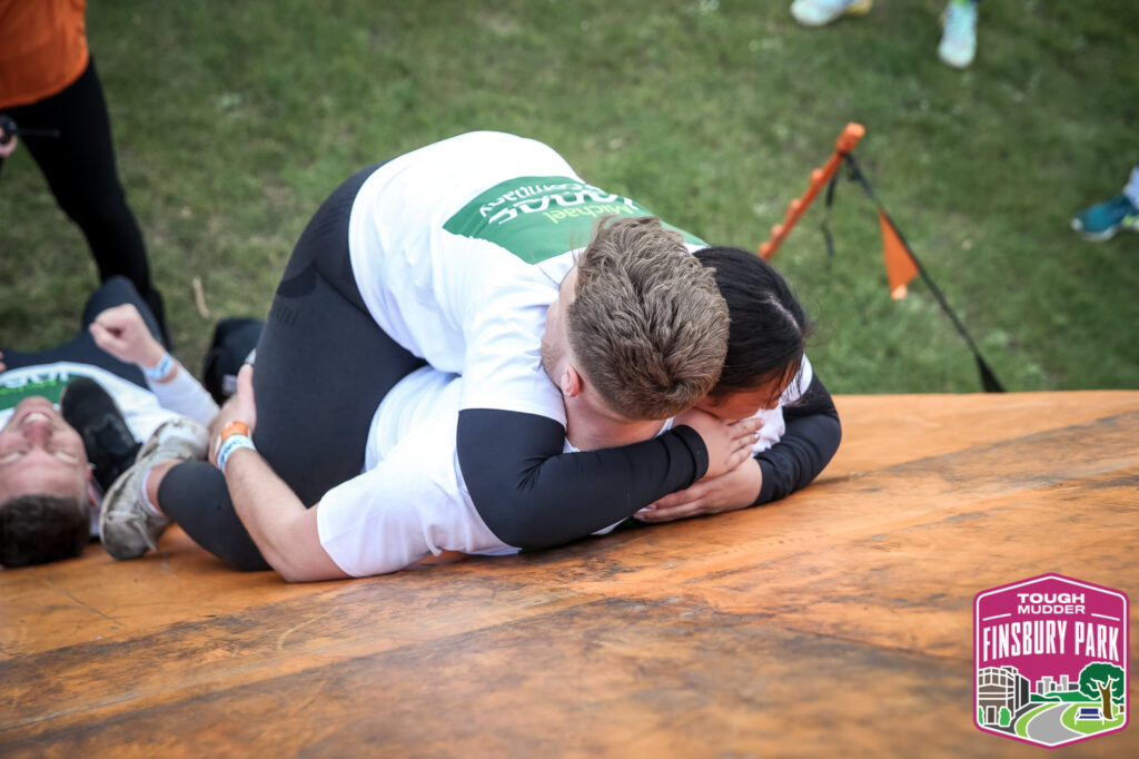 team mates man and woman hugging on obstacle